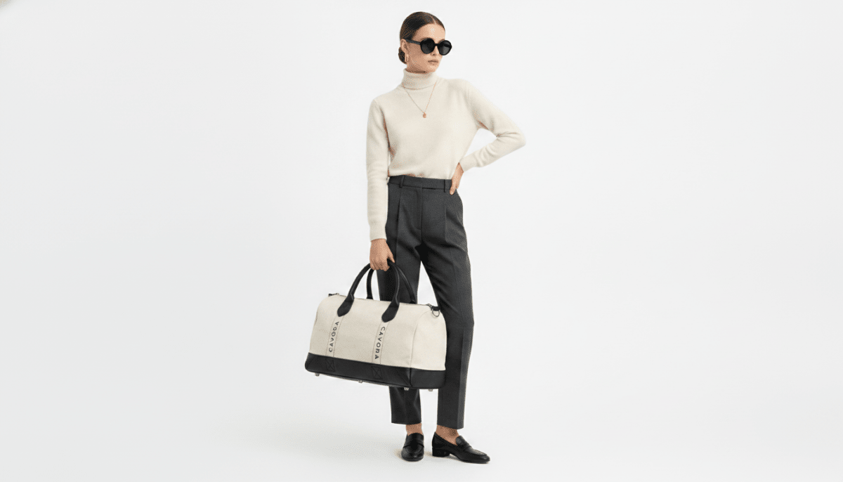 Person holding a black and white duffel bag against a white background